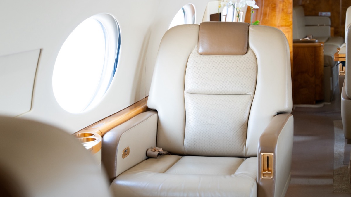 Gulfstream G450 cabin — ivory leather club seat beside the signature oval windows